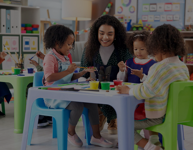 Children painting with teacher in classroom